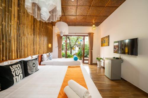 ein Wohnzimmer mit einem Sofa und einem TV in der Unterkunft An Bang Gold Coast Beach Villa in Hoi An