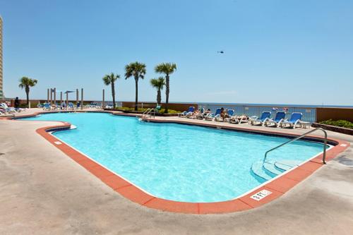 a swimming pool at a resort with people sitting in chairs at Sunrise Beach Resort V in Panama City Beach
