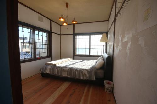 um quarto com uma cama e duas janelas em kODATEL コダテル 函館シーサイド em Hakodate