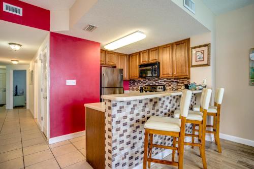 a kitchen with a bar with chairs and a red wall at Seychelles Beach Resort IV in Panama City Beach