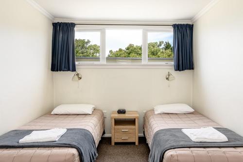 two twin beds in a room with a window at Motueka Garden Motel in Motueka