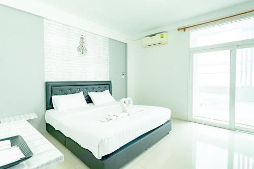 a white bedroom with a large bed and a desk at Central View Hostel in Hat Yai