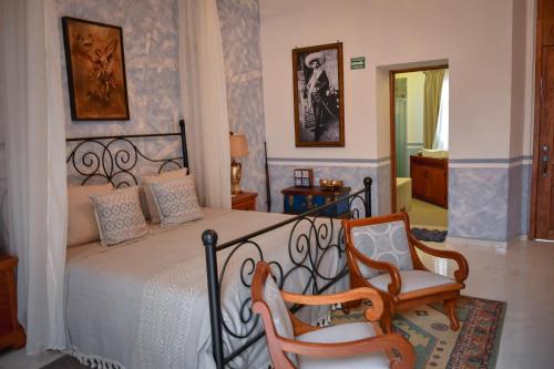 a bedroom with a bed and two chairs at Hotel Hacienda San Isidro in San Isidro Mazatepec