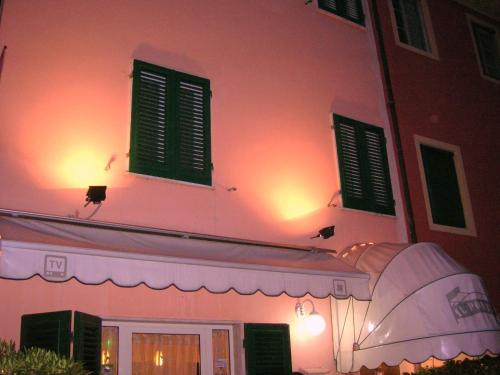 a pink building with green windows and a tent at Il Ponte Affittacamere in Lucca