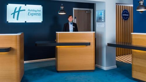 a man is standing in front of a bar at Holiday Inn Express Portsmouth – North, an IHG Hotel in Portsmouth
