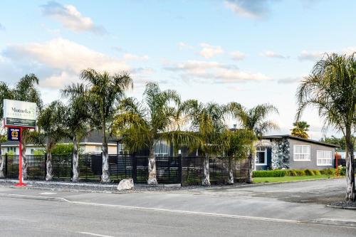 a street with palm trees in front of a building at Motueka Garden Motel in Motueka