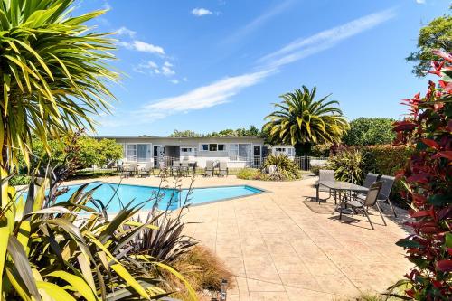 a backyard with a swimming pool and a house at Motueka Garden Motel in Motueka