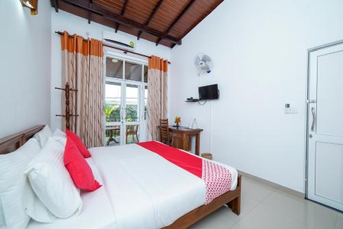 Schlafzimmer mit einem Bett mit roten Kissen und einem Fenster in der Unterkunft Dazzling Villa in Kandy