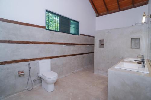 a bathroom with a toilet and a sink and a window at Green Residencies in Galle