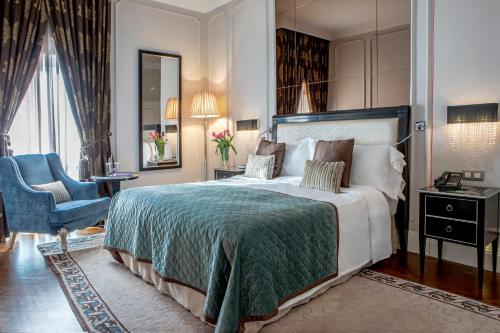 a bedroom with a large bed and a blue chair at InterContinental Porto - Palacio das Cardosas by IHG in Porto