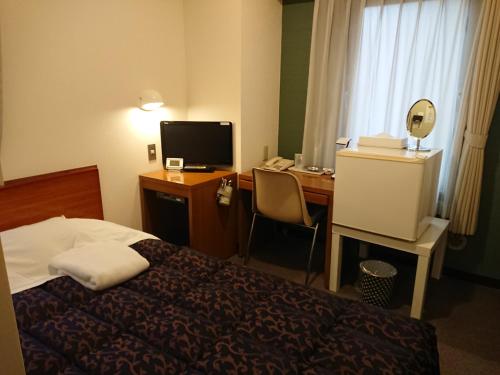 東京にあるレジデンス ホテル ウィル 新宿のベッド、デスク、コンピュータが備わるホテルルームです。