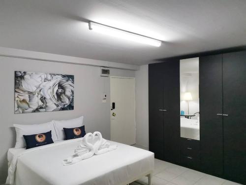 ein Schlafzimmer mit einem weißen Bett und einem schwarzen Schrank in der Unterkunft RoomQuest Bangkok Ratchada in Bangkok