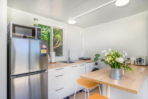 eine Küche mit einem Kühlschrank aus Edelstahl und einem Holztisch in der Unterkunft Cosy cabin to stay even better than Glamping in Pukekohe East