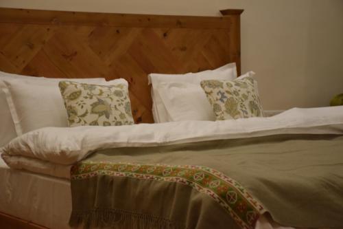 a bed with white pillows and a wooden headboard at Kudrat - A Boutique Homestay- Tirthan Valley in Banjār
