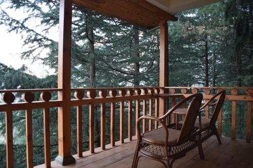 a rocking chair on the porch of a cabin at Kudrat - A Boutique Homestay- Tirthan Valley in Banjār