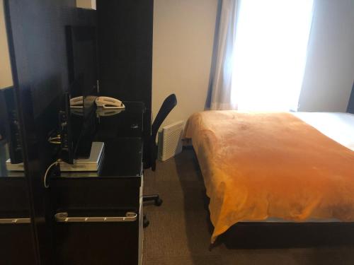 a bedroom with a bed and a desk with a phone at Green Rich Hotel Hamada Ekimae (Artificial hot spring Futamata Yunohana) in Hamada