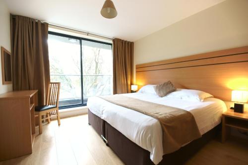 una camera con un grande letto e una grande finestra di Lodge Drive Serviced Apartments a Enfield