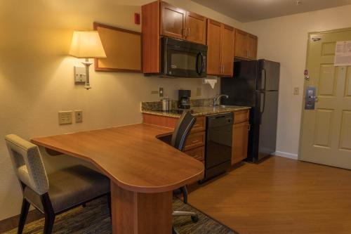 a small kitchen with a wooden table and a refrigerator at Candlewood Suites Abilene by IHG in Abilene