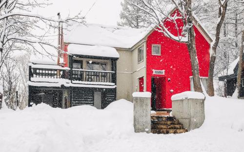 a house with a red door in the snow at Niseko Ski Lodge - Hirafu in Kutchan