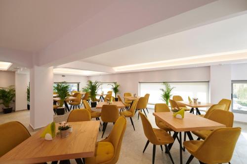 restauracja z drewnianymi stołami i żółtymi krzesłami w obiekcie Meni Apartments w Atenach