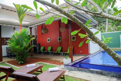 a patio with a pool and tables and chairs at Silver Ferns in Hikkaduwa