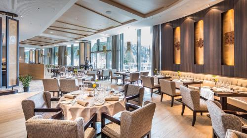 a restaurant with tables and chairs and windows at AlpenGold Hotel Davos in Davos