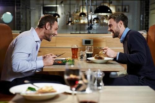 two men sitting at a table eating food at Holiday Inn London Brentford Lock by IHG in Brentford