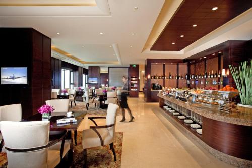 a restaurant with a bar with white chairs and tables at InterContinental Wuxi, an IHG Hotel in Wuxi