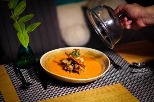 a person pouring a cup of soup into a bowl at Seaphere Pattaya Hotel by Elite Suites in Na Jomtien