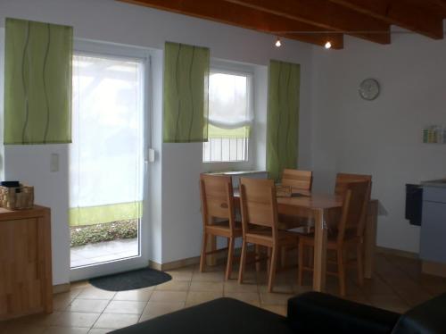 ein Esszimmer mit grünen Vorhängen sowie einem Tisch und Stühlen in der Unterkunft Ferienanlage Karolinenhof 2 in Haundorf