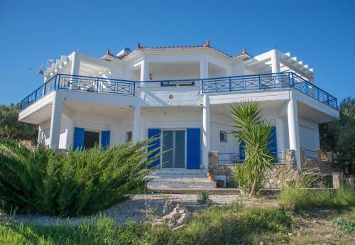 een wit huis met blauwe deuren en een balkon bij Villa Iremia in Chrani