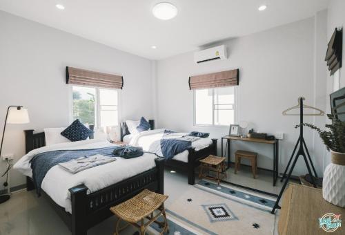 a bedroom with two beds and a table and two windows at PAI LAMUN VALLEY in Pai