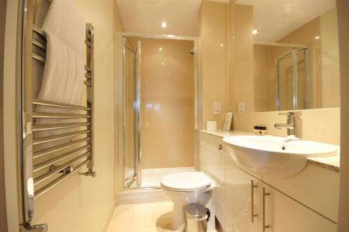 y baño con aseo, lavabo y ducha. en Lodge Drive Serviced Apartments en Enfield