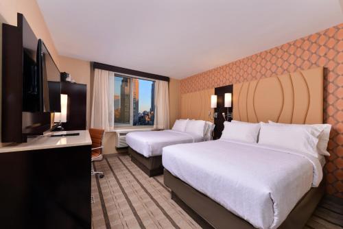 um quarto de hotel com duas camas e uma televisão de ecrã plano em Holiday Inn New York City - Times Square, an IHG Hotel em Nova Iorque