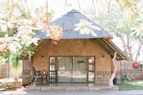 a small building with a roof with tables and chairs at Tshukudiba Game Lodge in Tom Burke