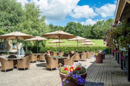 a row of tables and chairs with umbrellas and flowers at Holiday Inn Leeds Brighouse by IHG in Brighouse