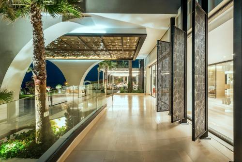 a hallway with a palm tree in a building at Mitsis Rodos Village in Kiotari
