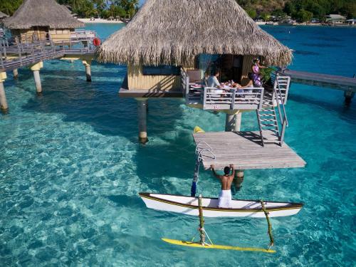 a person sitting on a surfboard in the water at InterContinental Bora Bora Le Moana Resort, an IHG Hotel in Bora Bora