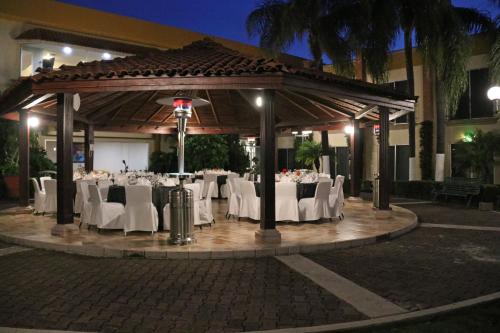 a gazebo with white tables and chairs at night at Holiday Inn La Piedad by IHG in La Piedad Cavadas