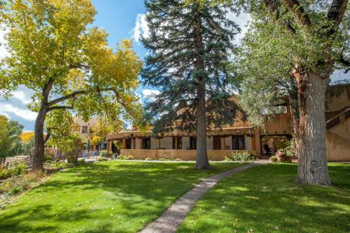 a green yard with trees in front of a building at Inn on La Loma Plaza in Taos