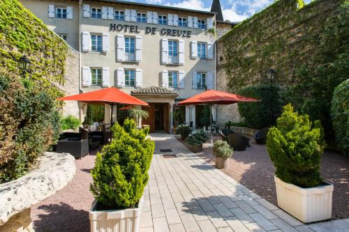 un hôtel avec des arbres et des parasols dans une cour dans l'établissement Demeures & Châteaux - Hôtel Greuze & Spa Tournus, à Tournus