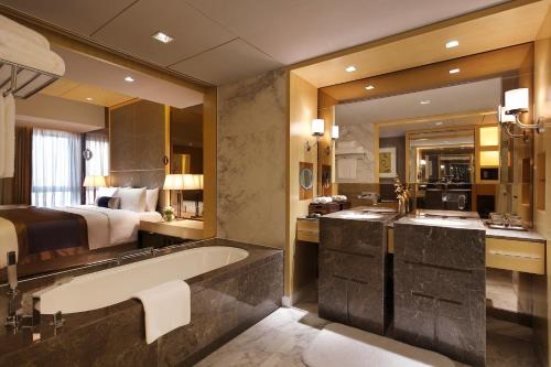a bathroom with a large tub and a bed at InterContinental Ningbo, an IHG Hotel in Ningbo