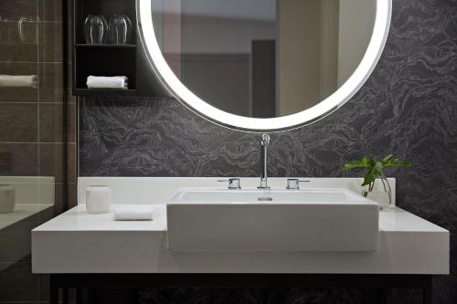 a white sink sitting under a mirror in a bathroom at Kimpton Sawyer Hotel, an IHG Hotel in Sacramento