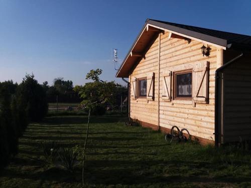 a small house in a field next to a building at Domek letniskowy - Świętne nad jeziorem Wilczyńskim in Wilczyn