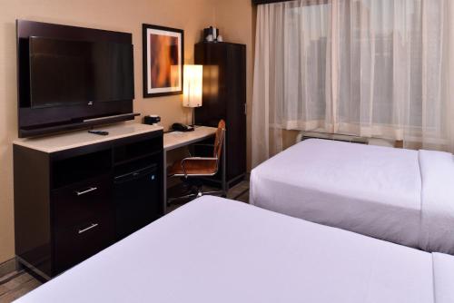 a hotel room with two beds and a desk with a television at Holiday Inn New York City - Times Square by IHG in New York