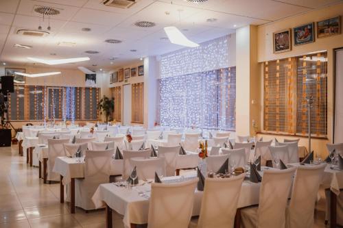 Hotel Galaksija Trebnje في Trebnje: قاعة احتفالات بالطاولات البيضاء والكراسي