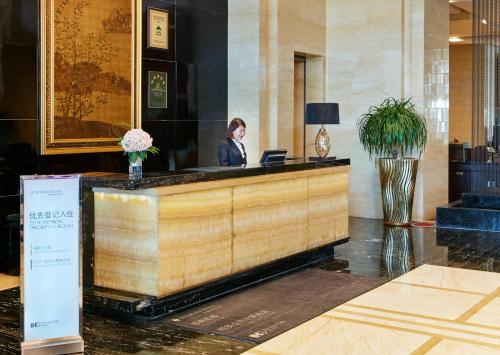 a woman sitting at a reception desk in a lobby at InterContinental Shijiazhuang by IHG in Shijiazhuang