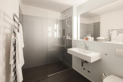 La salle de bains blanche est pourvue d'un lavabo et d'un miroir. dans l'établissement Baseltor Hotel & Restaurant, à Soleure