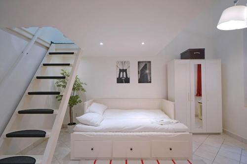 a room with a white bed and a staircase at V27 Vadász Apartment in Budapest