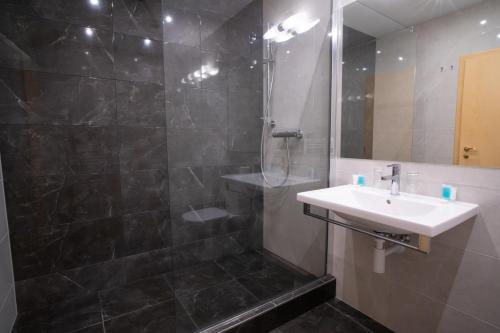 a bathroom with a shower, sink, and mirror at TeleDom Hotel in Košice
